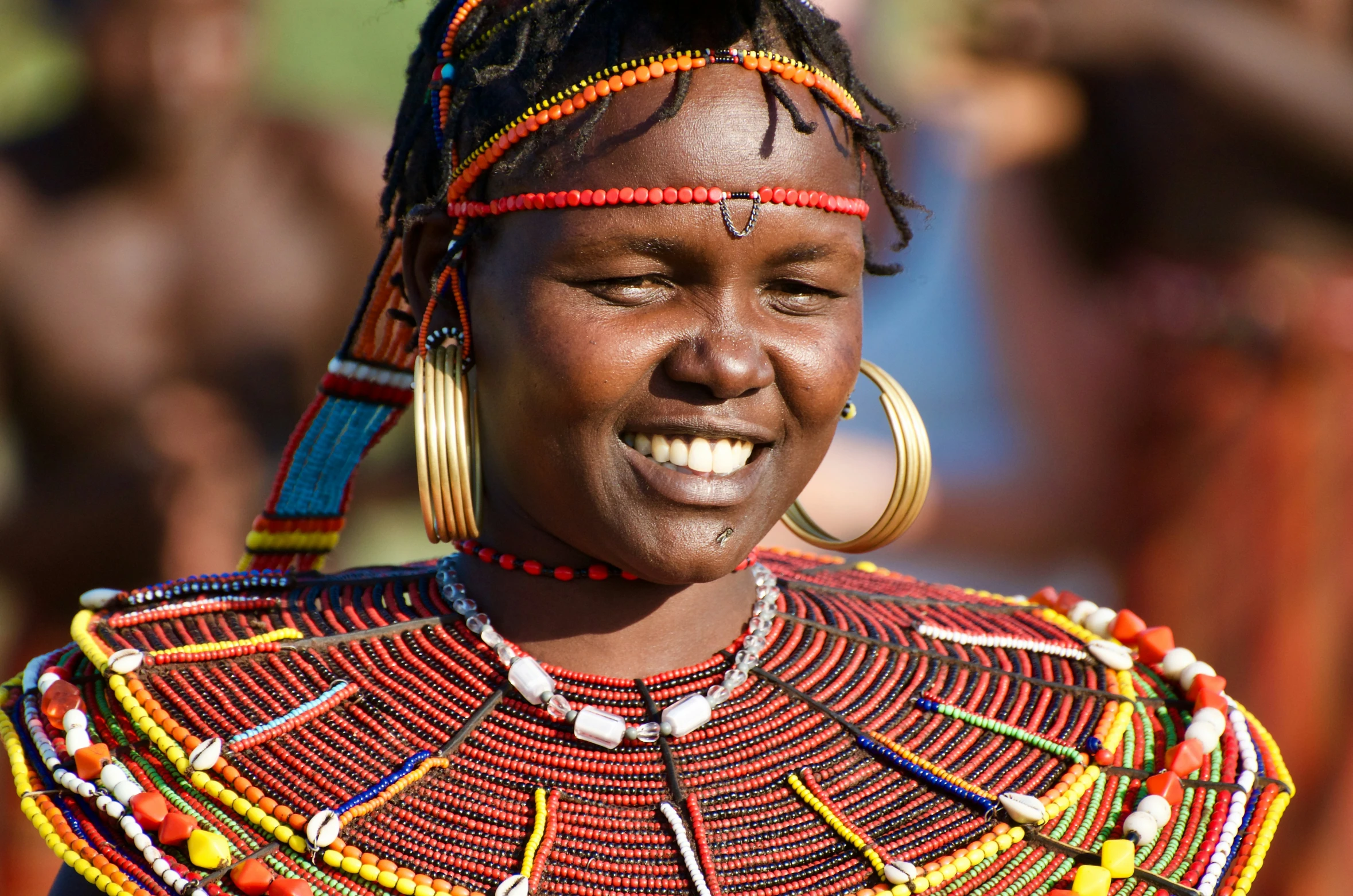 a woman wearing colorful necklaces smiles into the camera