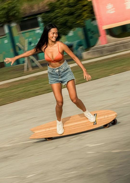 a woman in shorts and an orange top is riding a surfboard