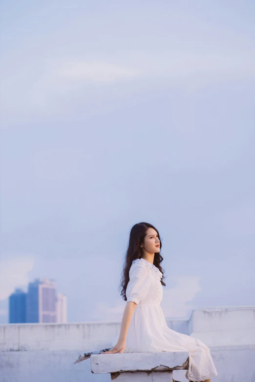 the woman in white dress sits on the roof