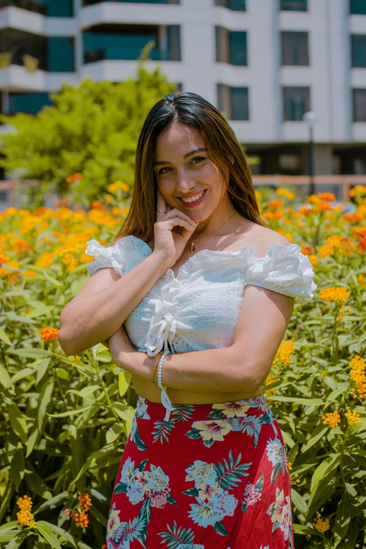 a woman posing in front of flowers with her arms crossed