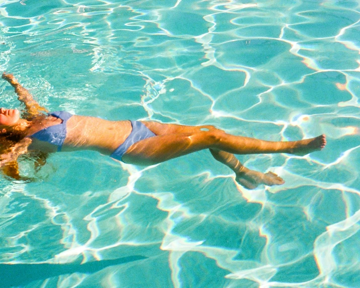 a girl floating in the blue water in a bikini