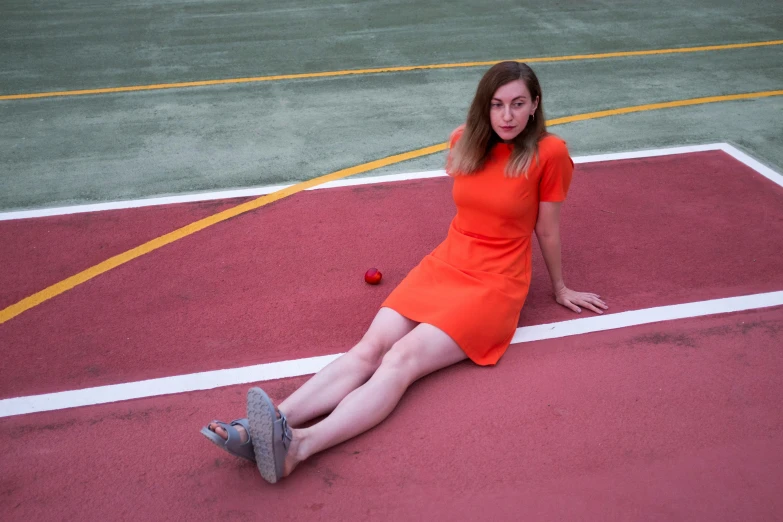 woman in bright orange dress sitting on tennis court