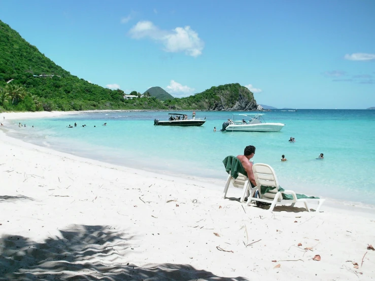 a person sitting on a beach in front of boats