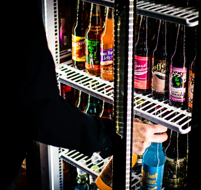 a man reaches into the fridge to grab a beverage