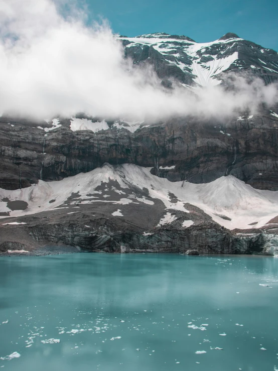 a snow - covered mountain overlooks water in front of mountains