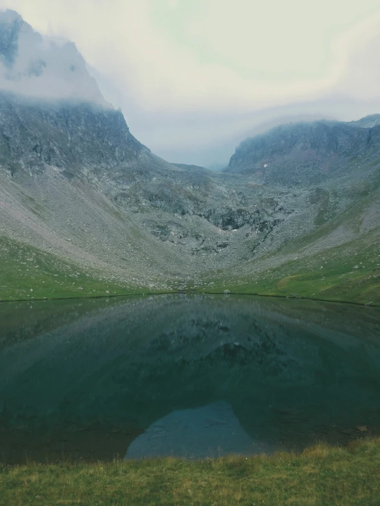 a mountain with green grass and a lake in it