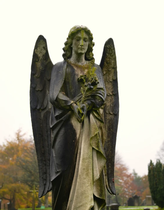 a statue stands next to a cemetery