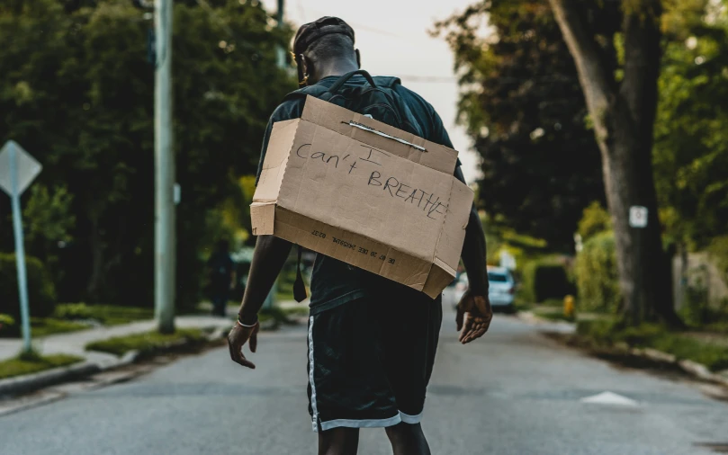 a man walks down the street with a cardboard box on his head