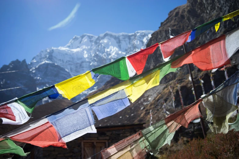 many multi colored flags hang in front of the mountain