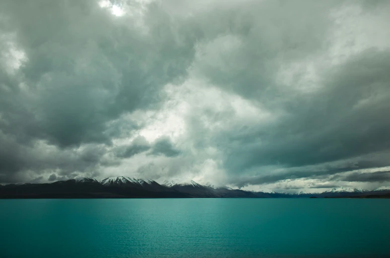 the sun shines through clouds over a calm lake