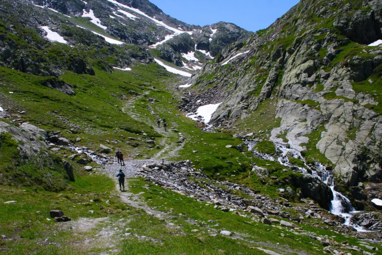 the man is walking up a path to a waterfall