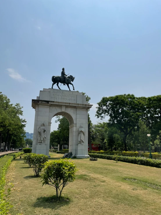 a statue in the middle of a field with trees around it