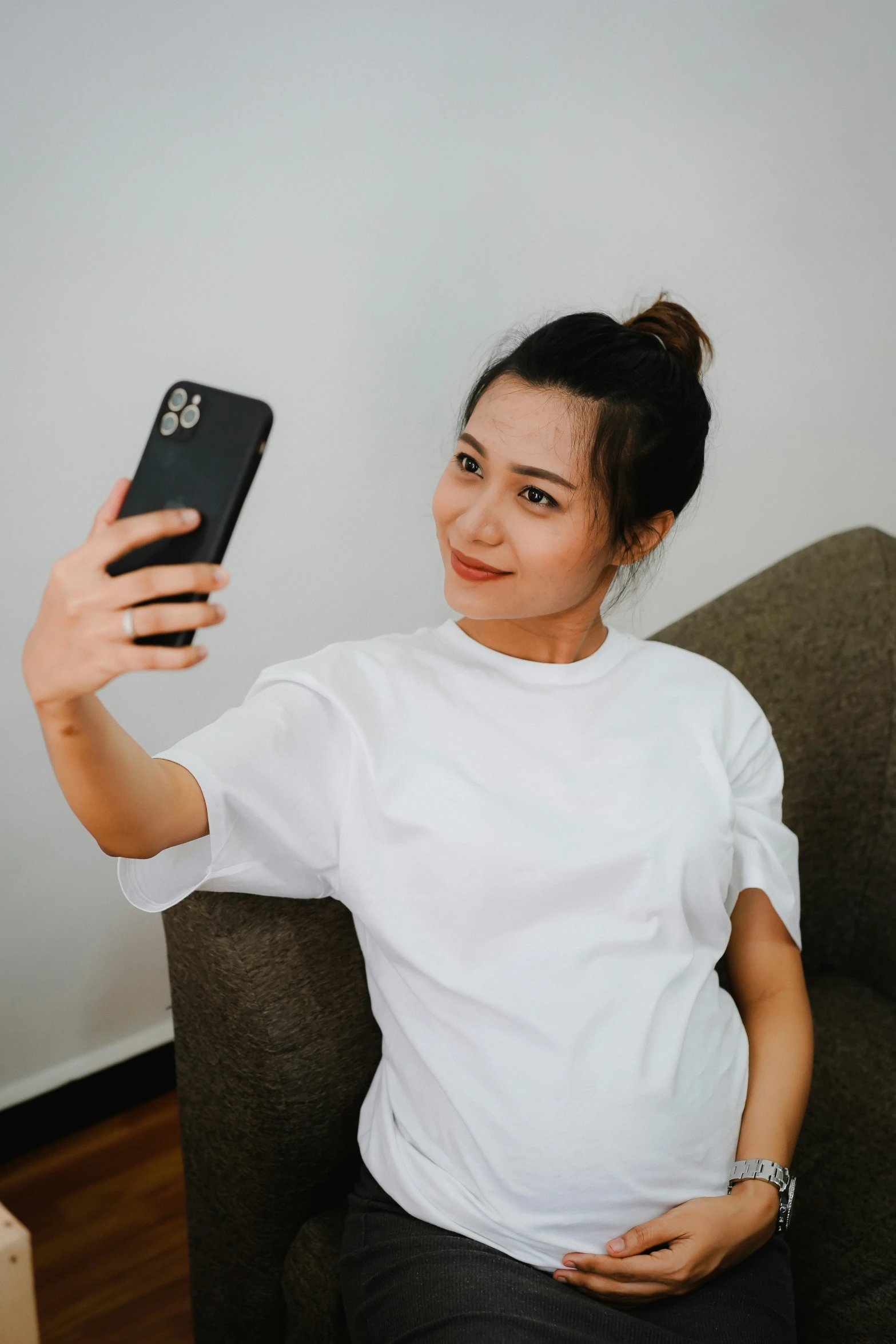 a woman is sitting in a chair while taking a selfie