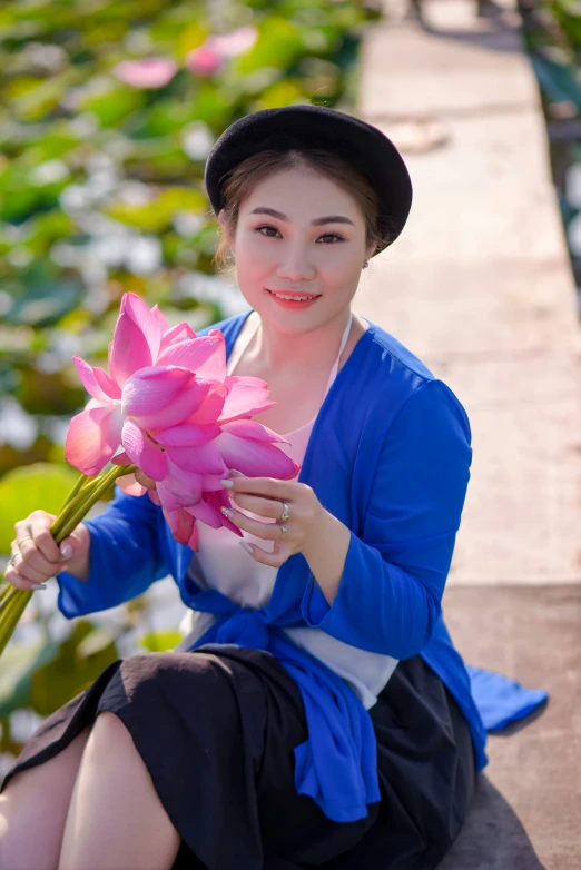 the woman is sitting on a stone wall with a pink rose