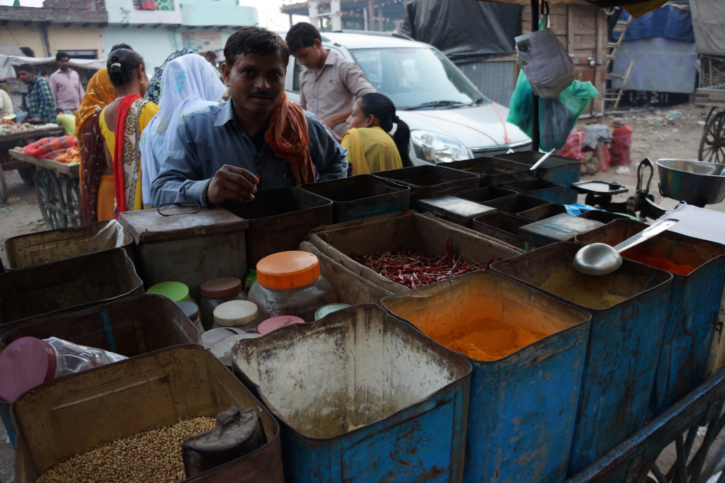 a man standing behind a blue wagon with containers of food in it