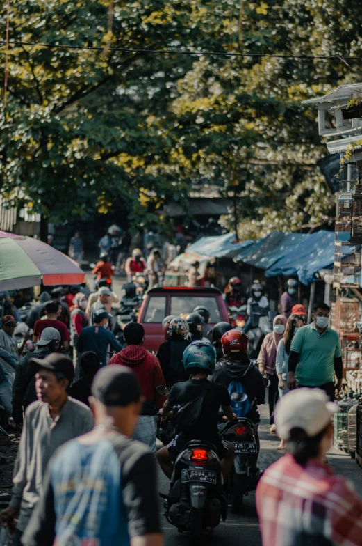 a crowded street filled with people walking and riding motorcycles