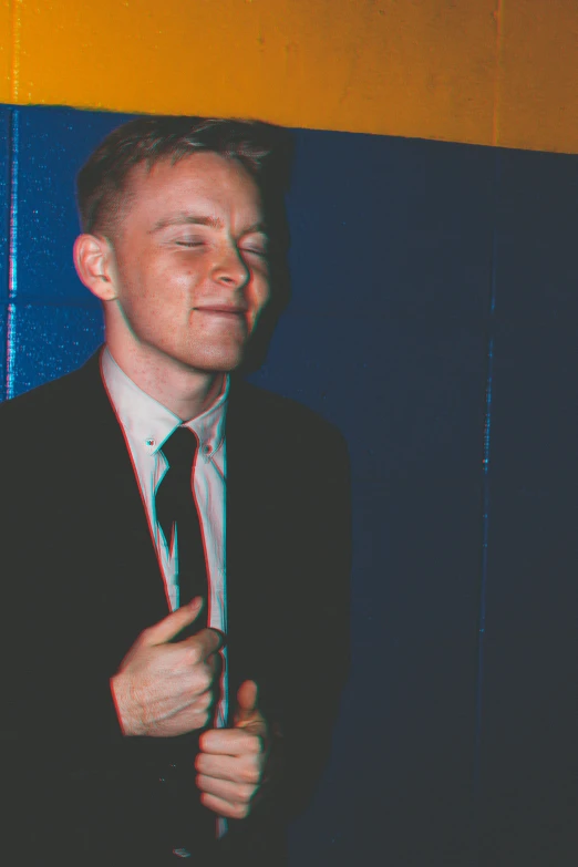 a man standing in front of a wall wearing a suit and tie