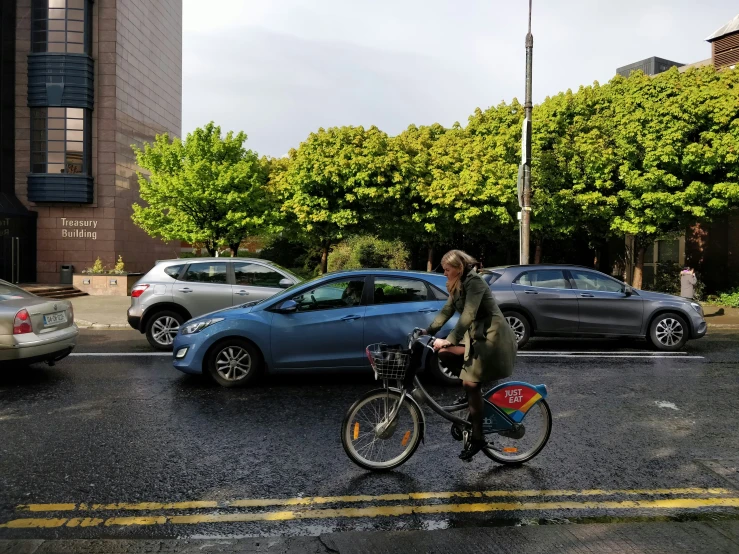 a person riding a bike on a street next to a few cars