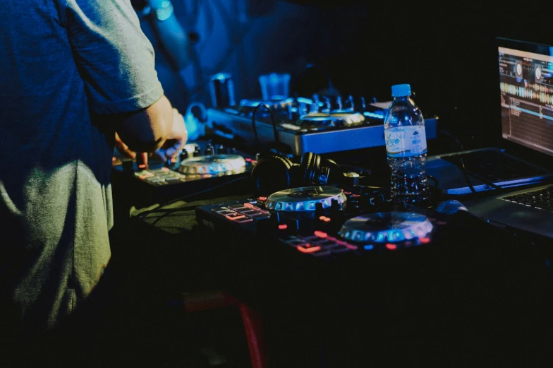 a dj standing near a laptop computer next to the dj's headphones