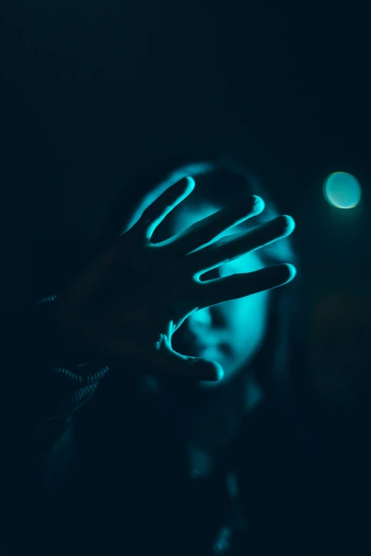 a man holding his hand up to the dark with blue light coming from the fingers