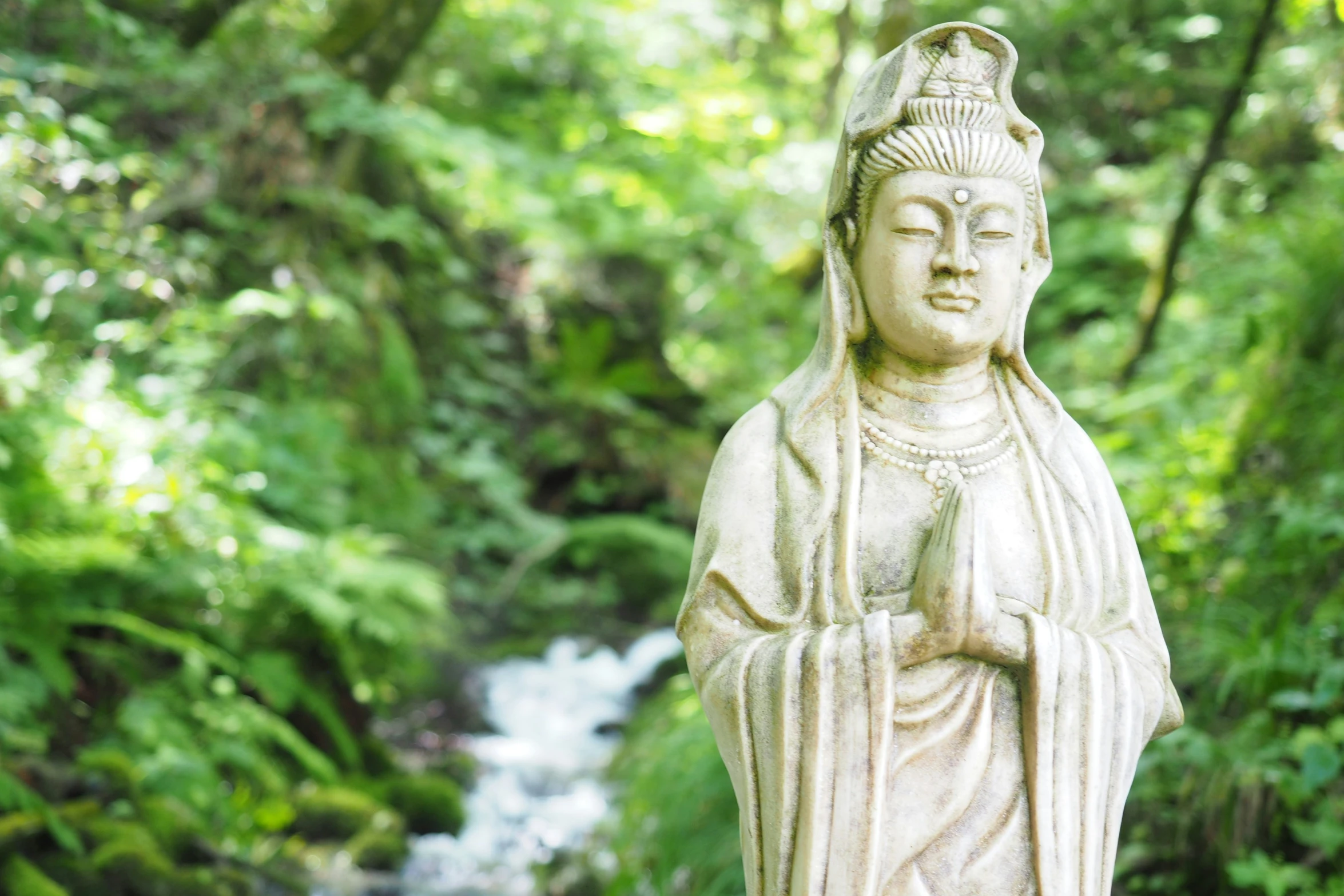 a statue of a buddha by a stream