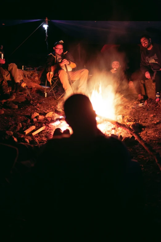 a group of people stand around a camp fire