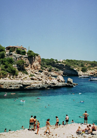 many people relaxing and swimming at a beautiful beach
