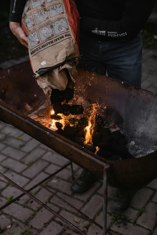 person on street cooking a small pot in charcoal