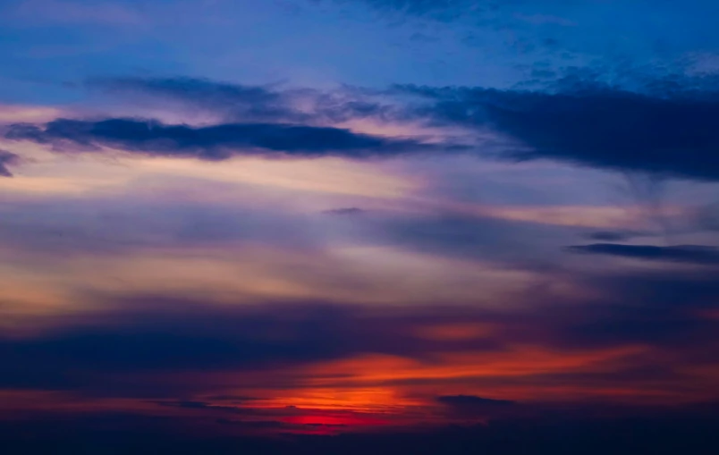 red and blue sunset behind a sailboat