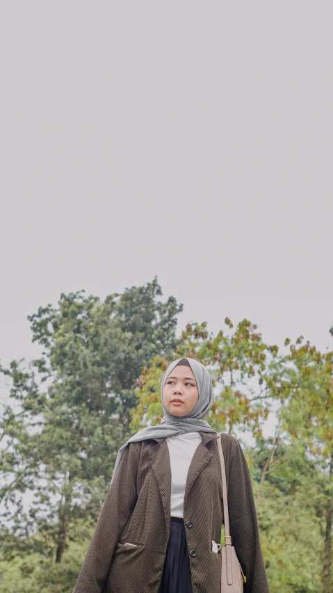 a woman is standing on a sidewalk near trees