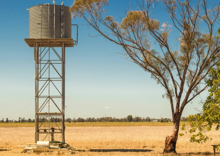 an old fashioned metal water tower and field in the background