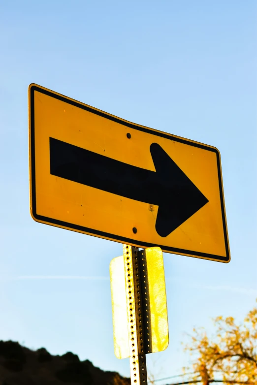 an upside down yellow sign displaying a right arrow