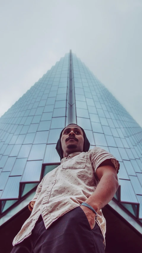 a man wearing an unisex shirt is standing outside a large building