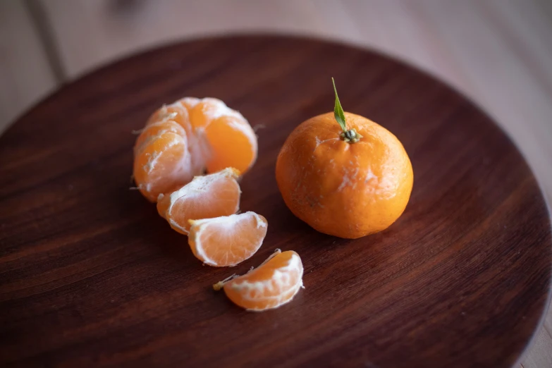 three tangerine halves are on a wooden plate