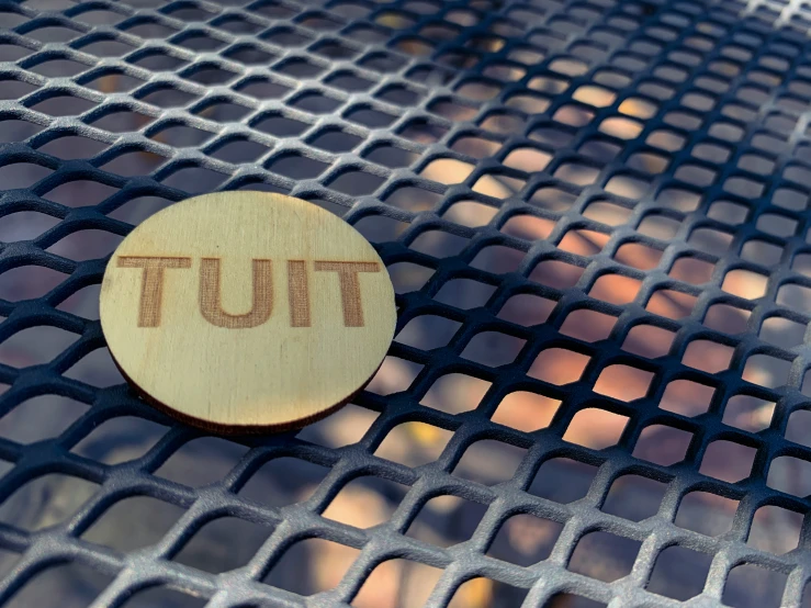 a small wooden piece with the word tut in the middle on a mosaic surface