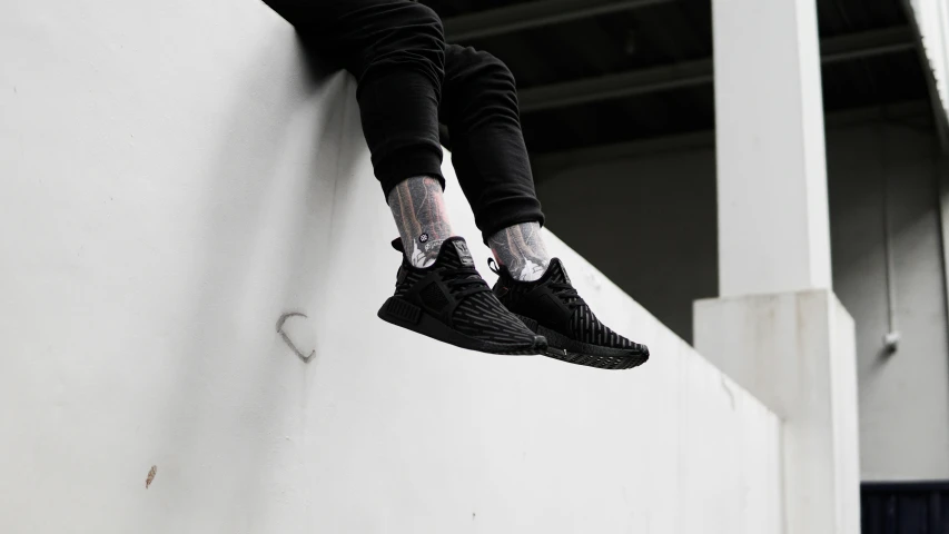 a person in black sweats and sneakers hanging off the side of a building