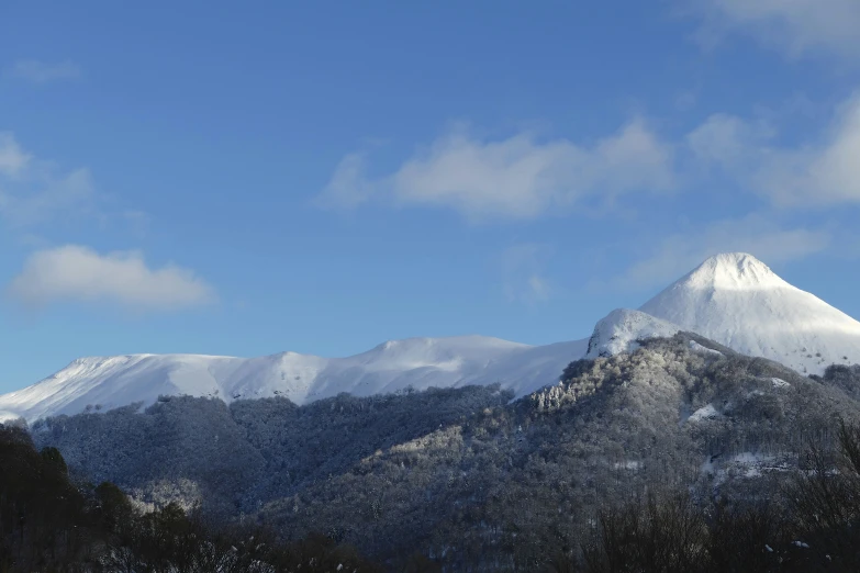 snow covered mountains and trees are seen against a clear blue sky