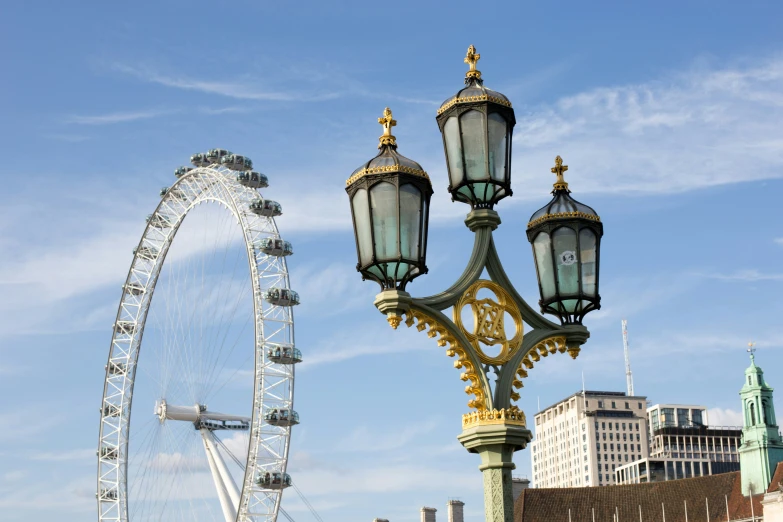 an ornate street light near a tall ferris wheel