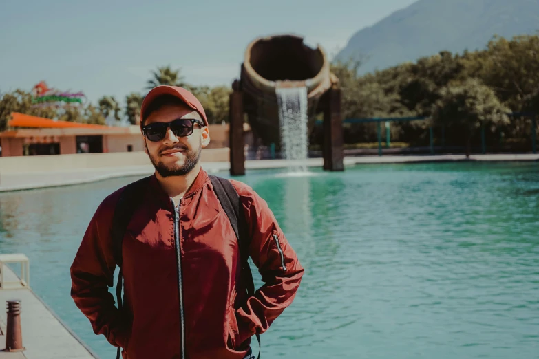 a man in a red jacket next to a large water fountain