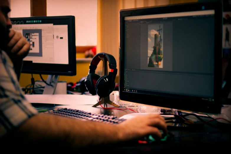 a person sitting in front of two computer monitors