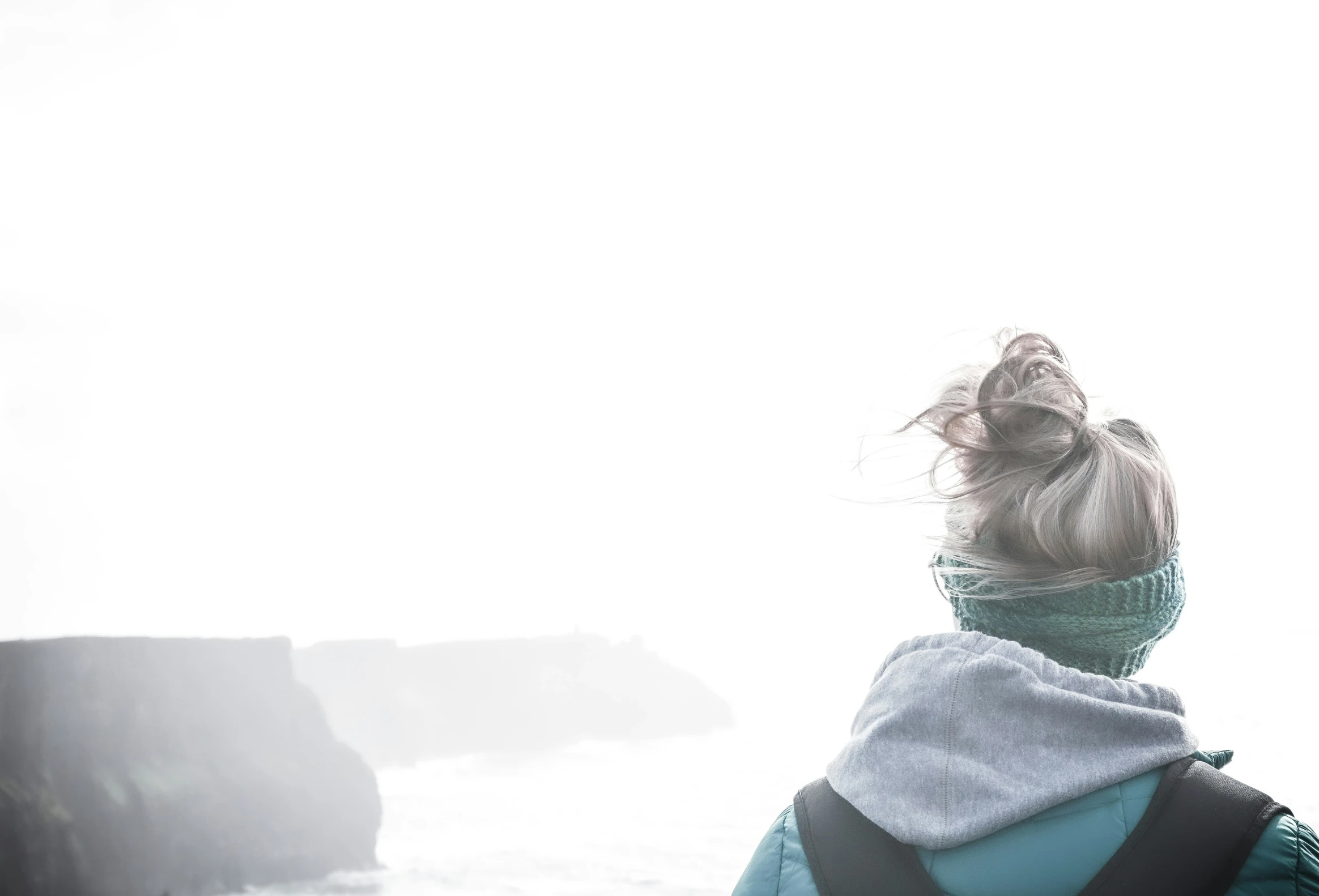 a woman with a towel on her head staring at the ocean