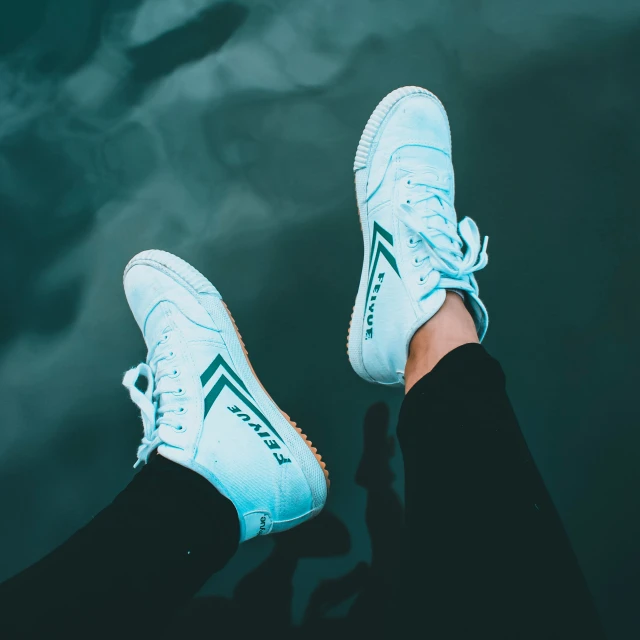 person's foot wearing blue sneakers with sky in background