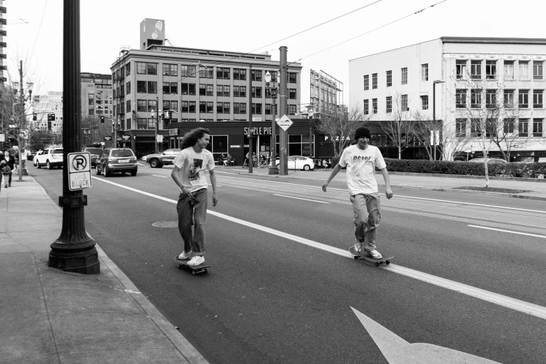 three people are riding skateboards down the street