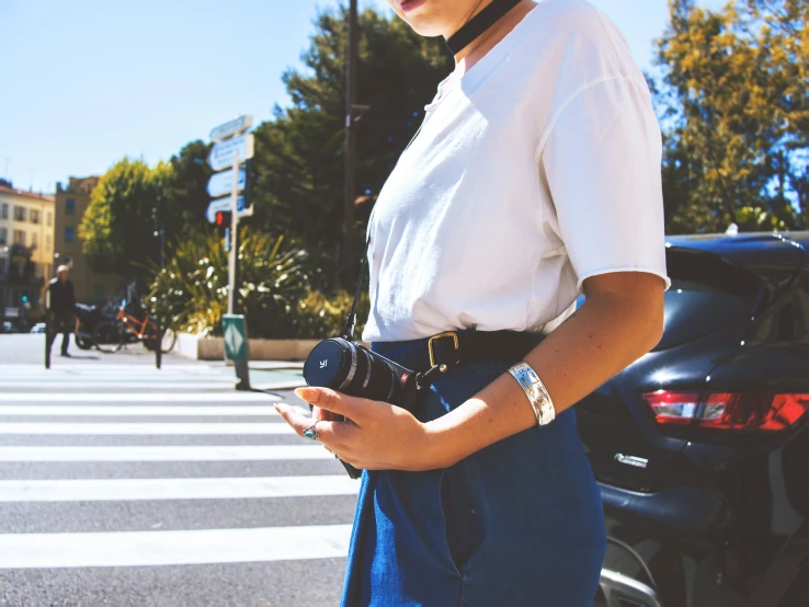 a woman is holding a cell phone while standing at the street