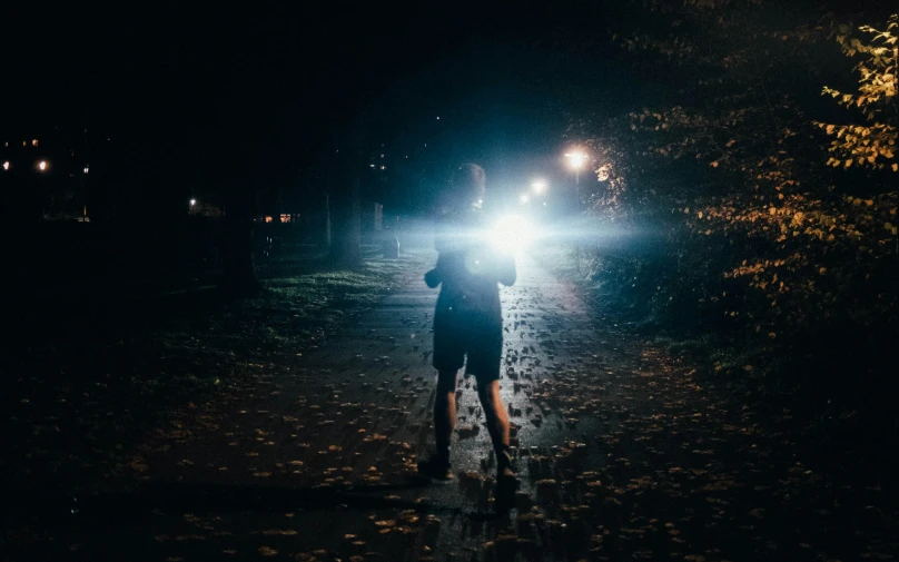 a woman riding on the back of a bicycle down a rain covered street at night