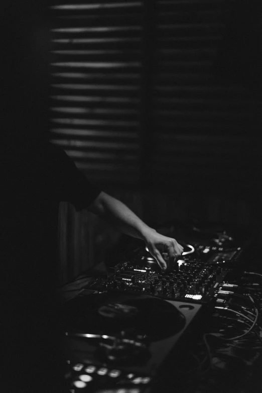 two hands using dj equipment in black and white