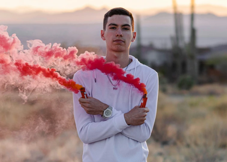 a man holding up two sticks with red smoke coming out