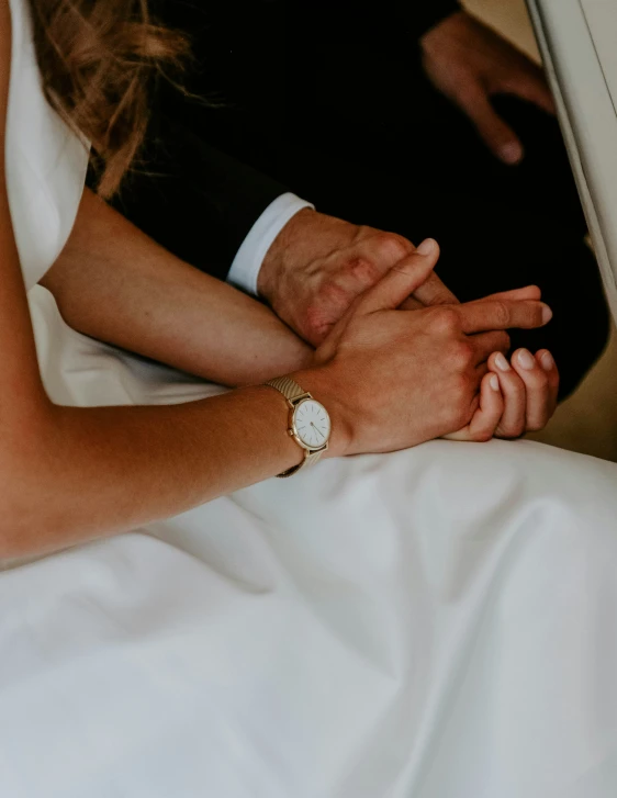 the hands of two people on a bed