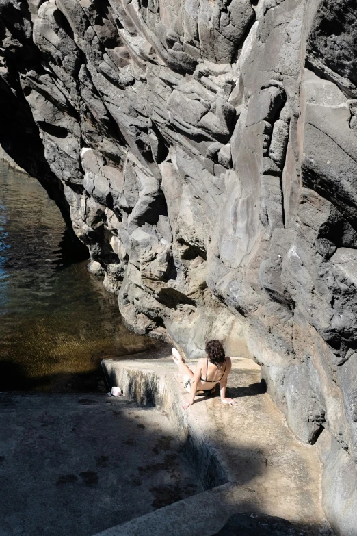 a boy sitting on some steps next to the water