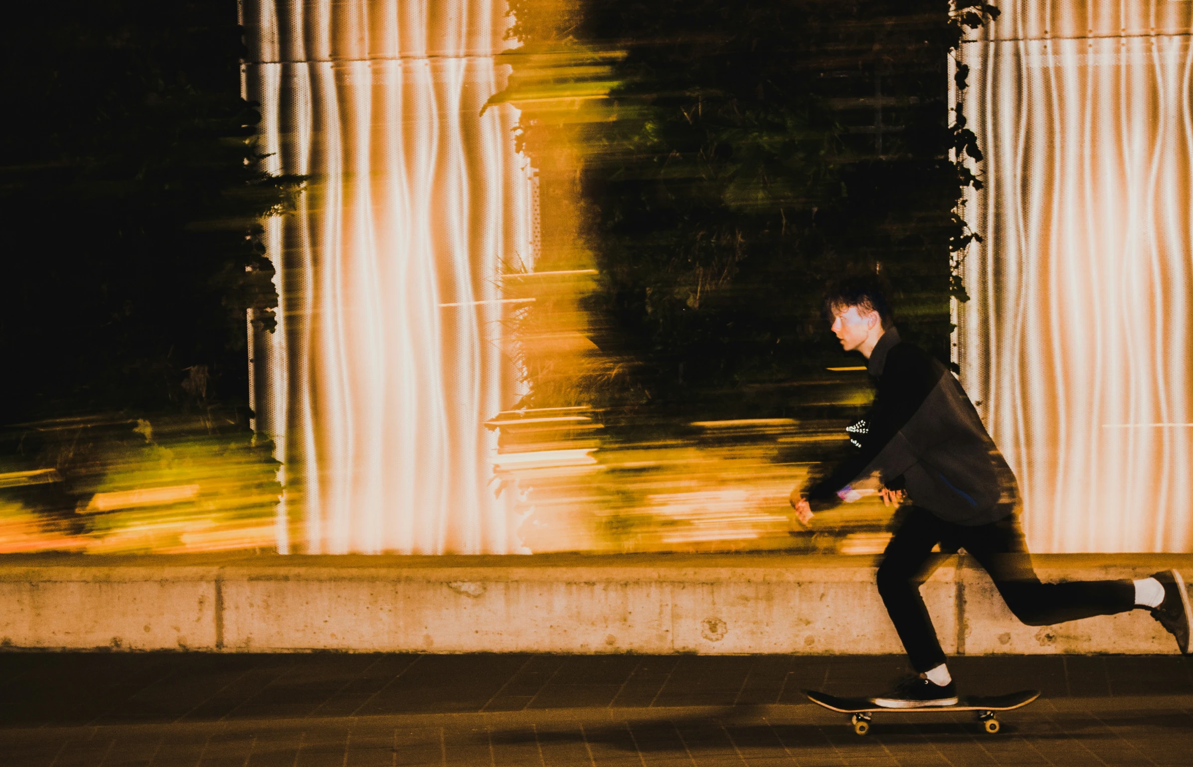 a man in black jacket on skateboard near building